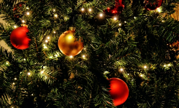 close up image of pine tree with colorful round ornaments and lights