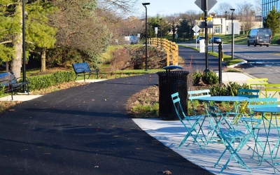 cement pathway with brightly colored tables and chairs, benches and a trash receptacle