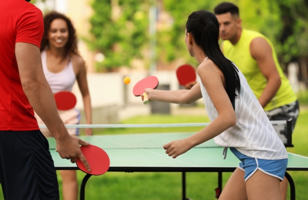 four people playing ping pong outdoors