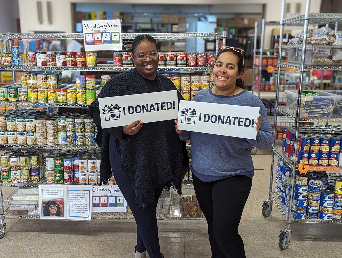 two people standing in front of racks of food holding "I DONATED" signs
