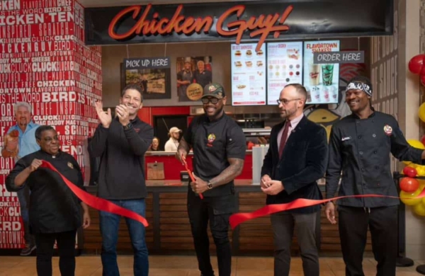 group of people cutting a red ribbon in front of Chicken Guy storefront